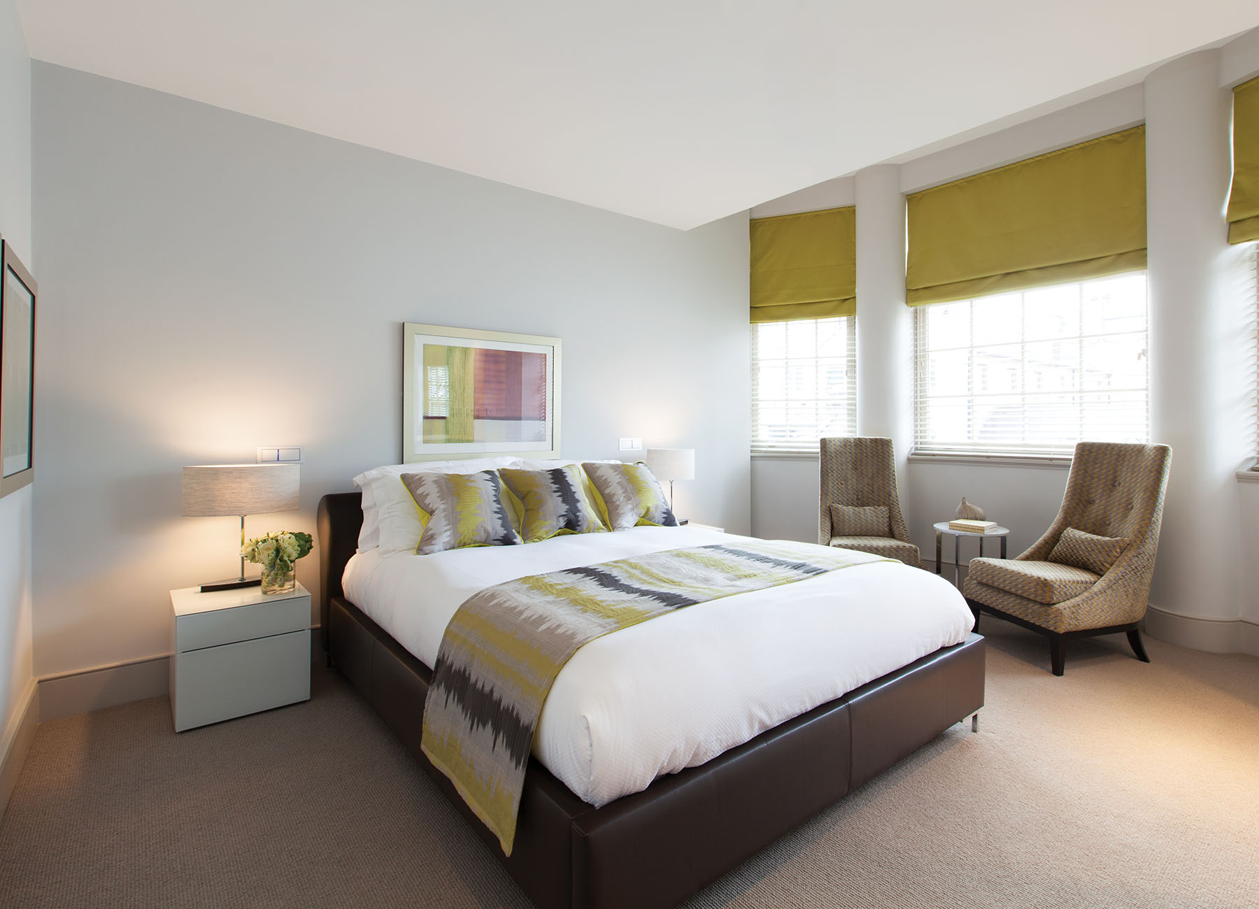 AKA Marylebone furnished apartment bedroom with king bed, yellow blinds, and luxury chairs