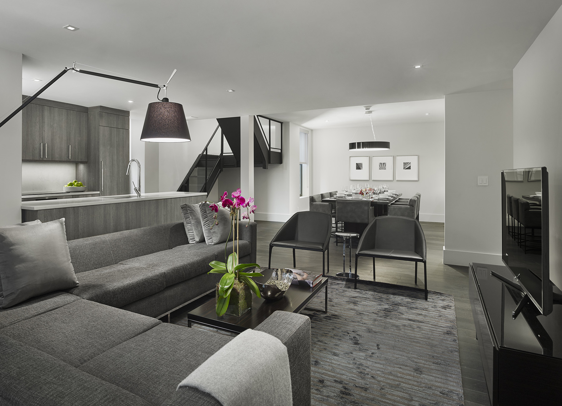 AKA Times Square bilevel penthouse lounge with modern gray furniture and view into the kitchen