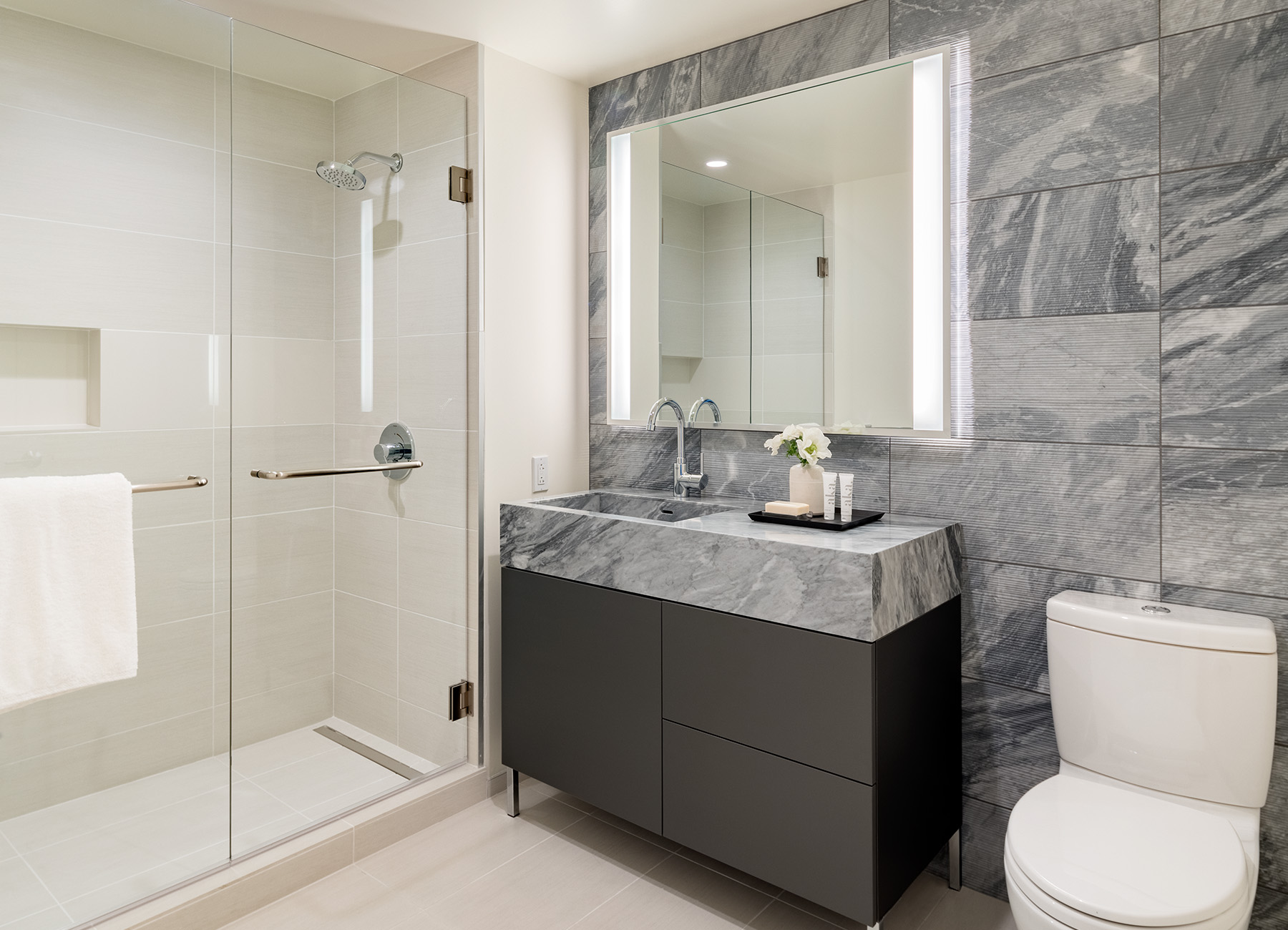 AKA West Hollywood apartment bathroom with dark gray marble sink and white tile shower