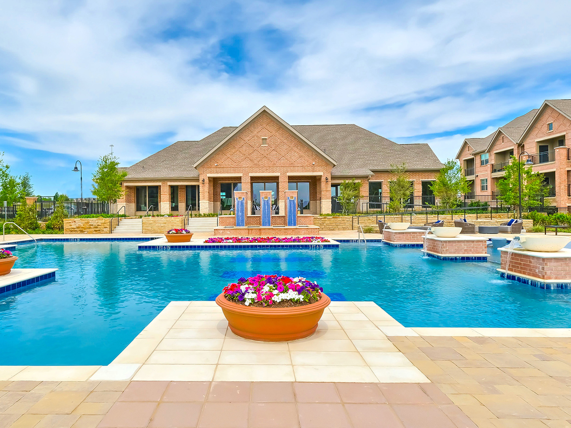 The pool area with flower garden at AVE Las Colinas apartment community