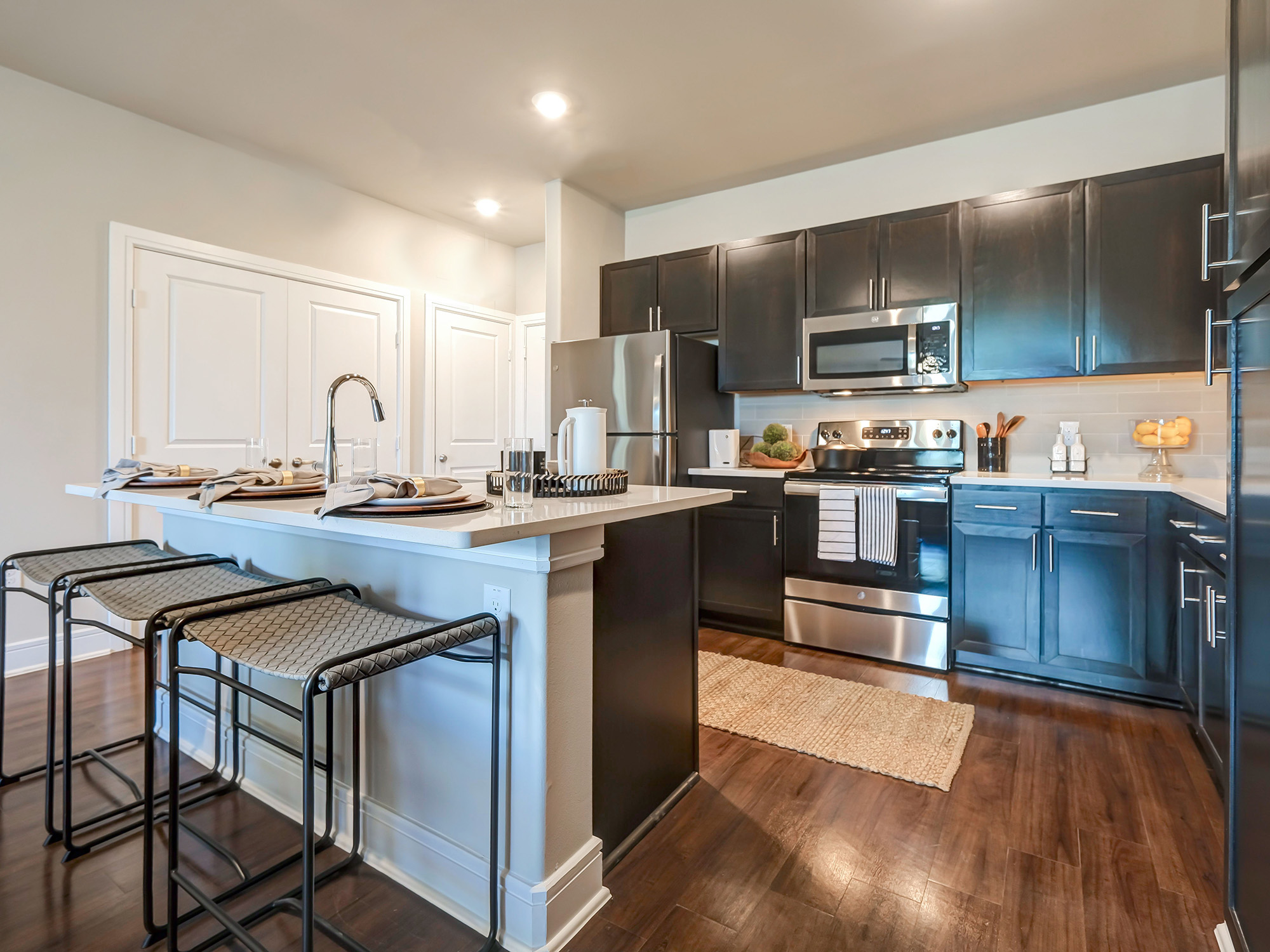 Furnished kitchen with counter and bar stool seating at AVE Las Colinas apartment community. 