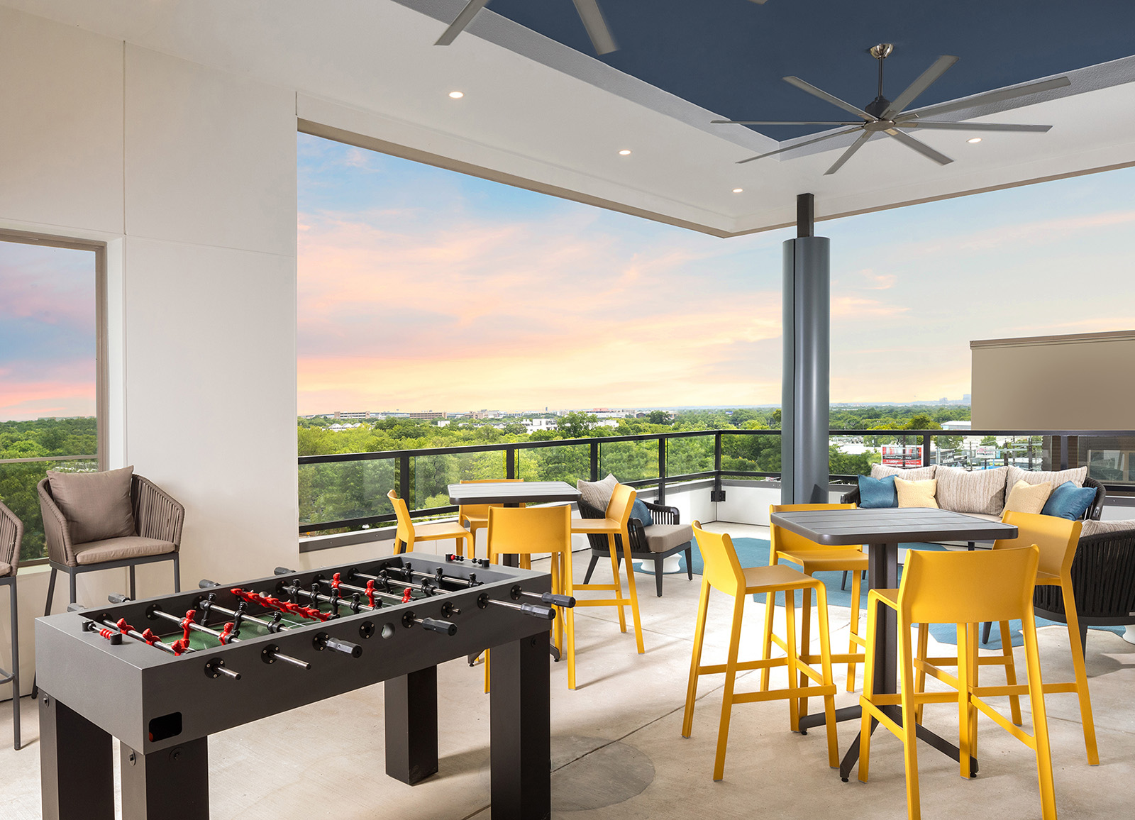 Open air rooftop lounge with yellow chairs, table game, and view of horizon at AVE Austin apartment building. 