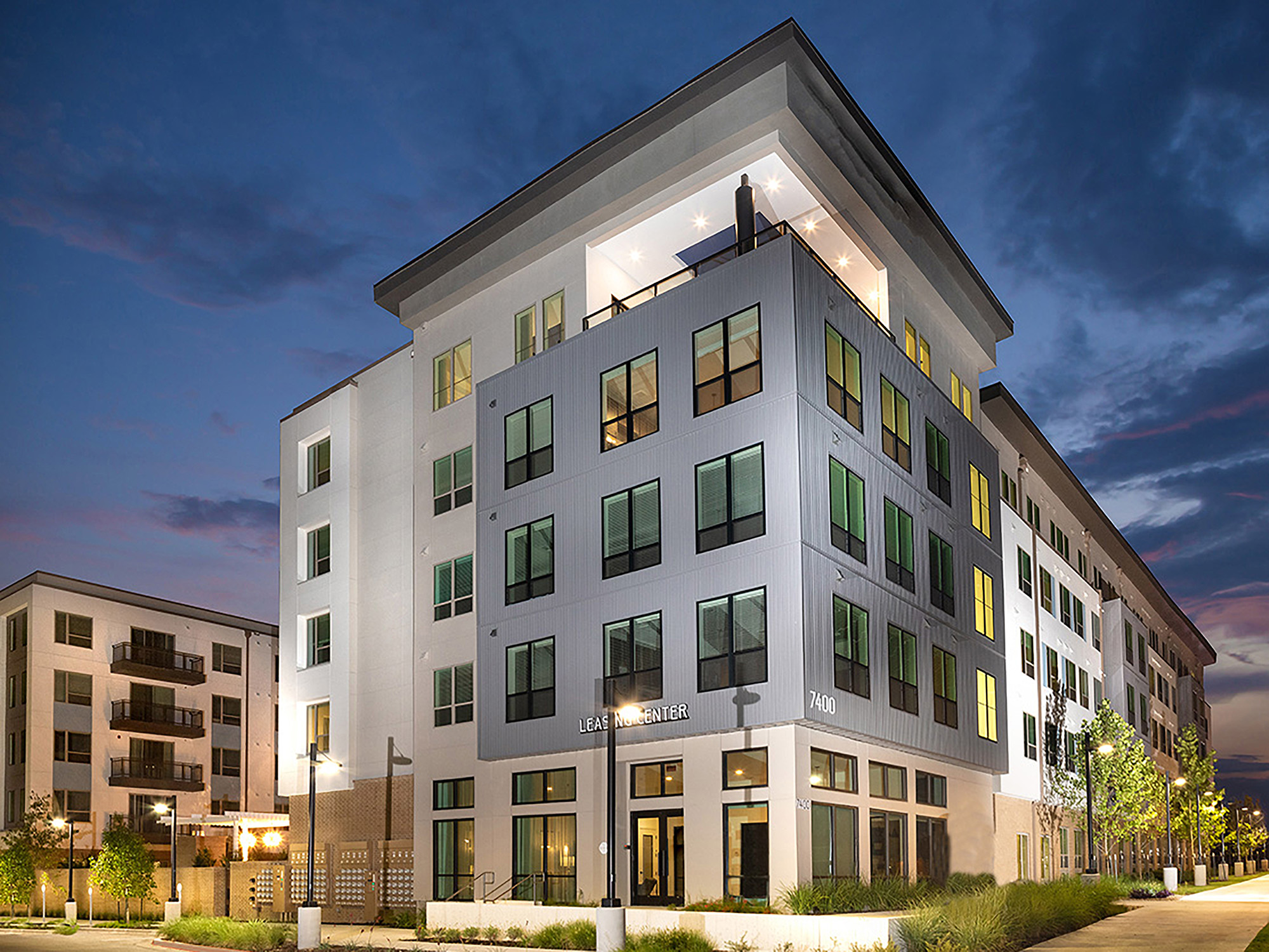 AVE Austin 5-story apartment building exterior façade with deep blue night sky at evening time.